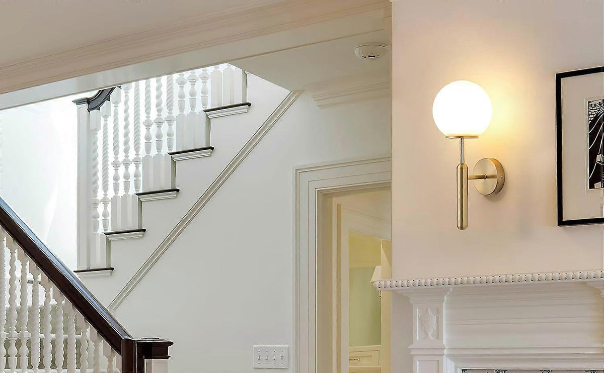 Pair of gold metal wall sconces with fabric shades lit on a wall