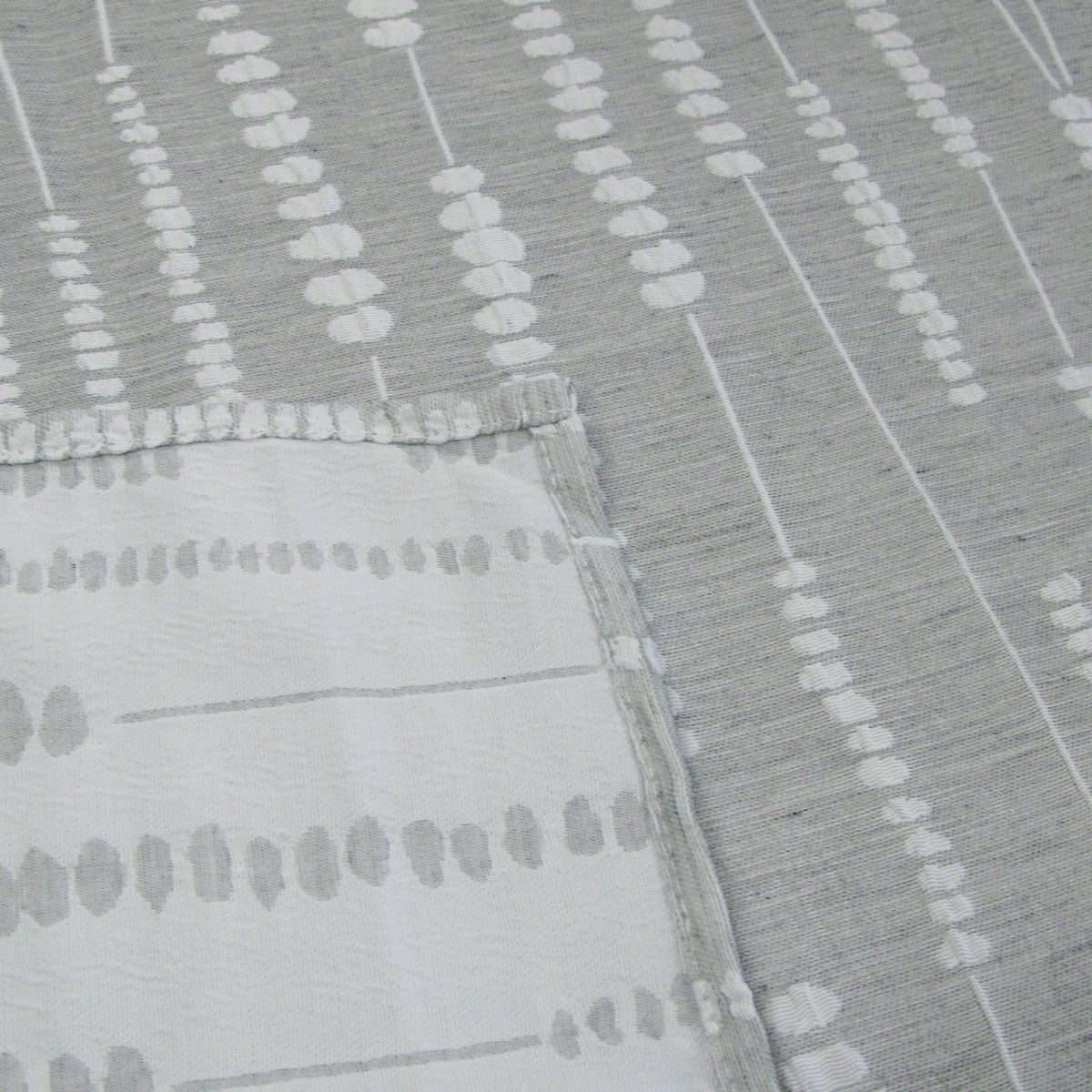 Grey and white jacquard polyester tablecloth laid over a rectangular dining table