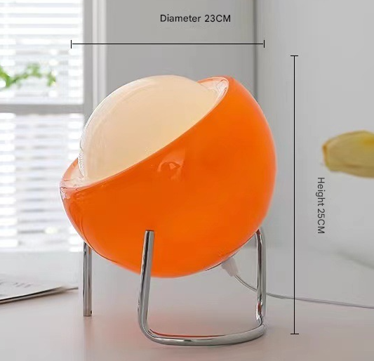 Small orange glass and iron table lamp glowing warm on a shelf