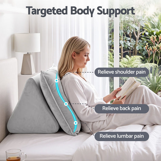 Grey velvet back support pillow with armrests propped against a bedhead