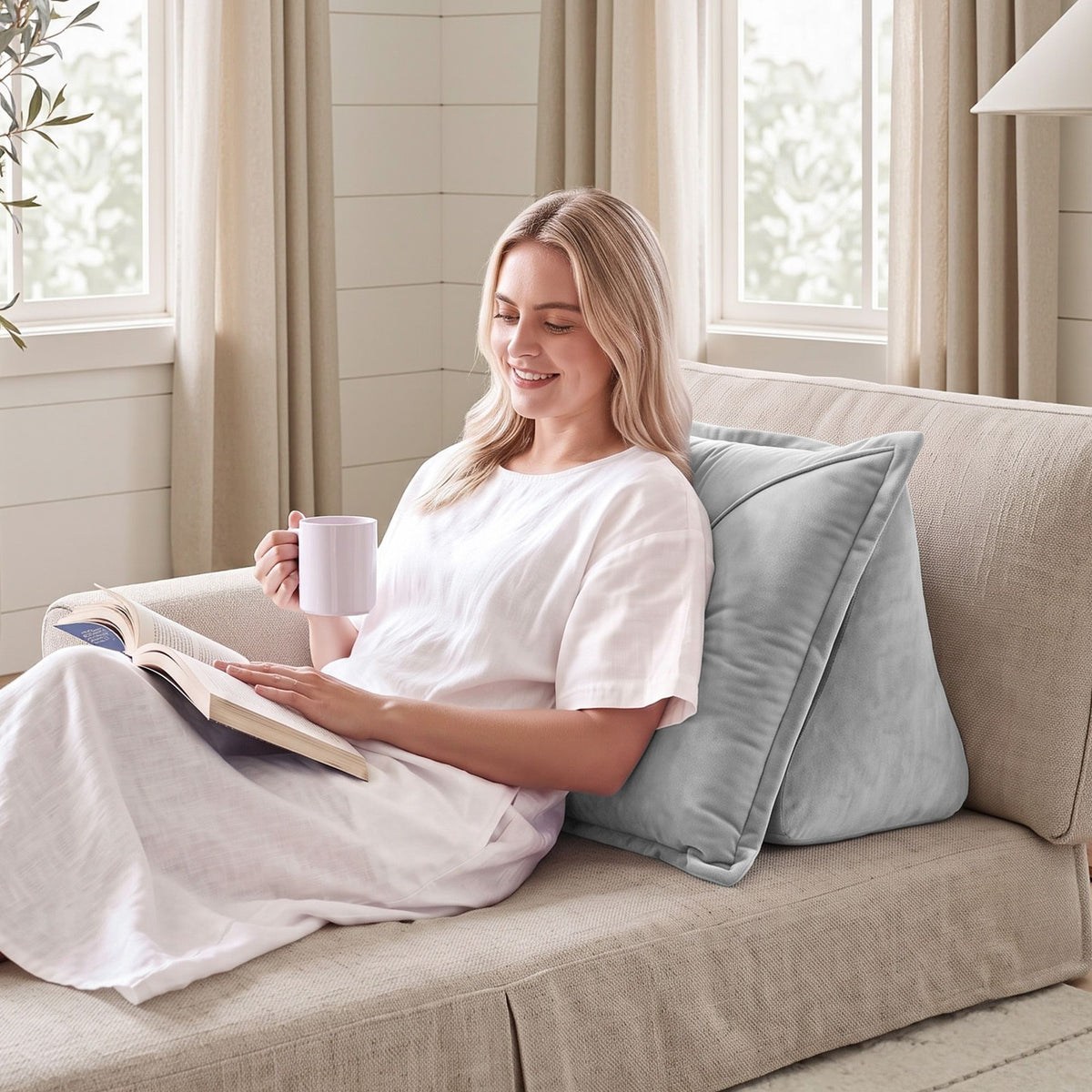 Grey velvet back support pillow with armrests propped against a bedhead