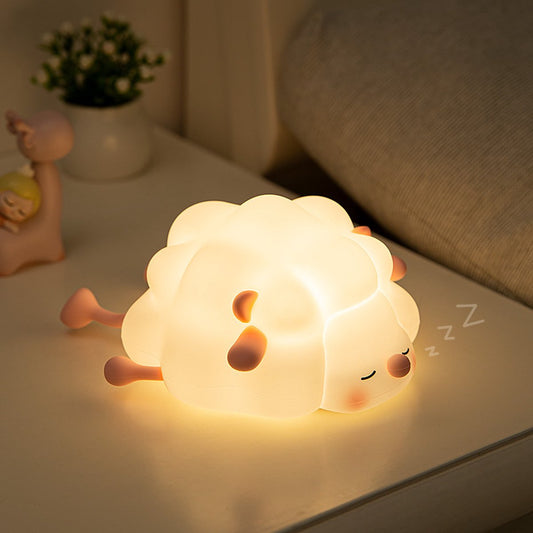 Soft rubber sheep night light glowing warm white on a bedside surface