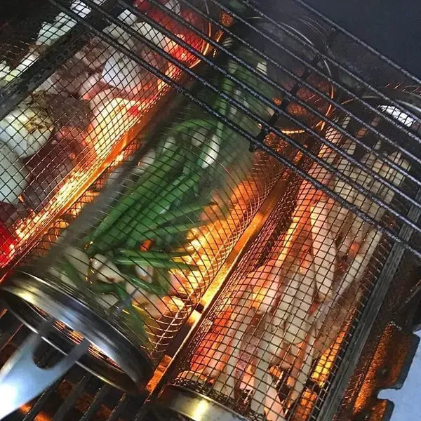 Cylindrical stainless steel mesh grill basket filled with vegetables on a barbecue