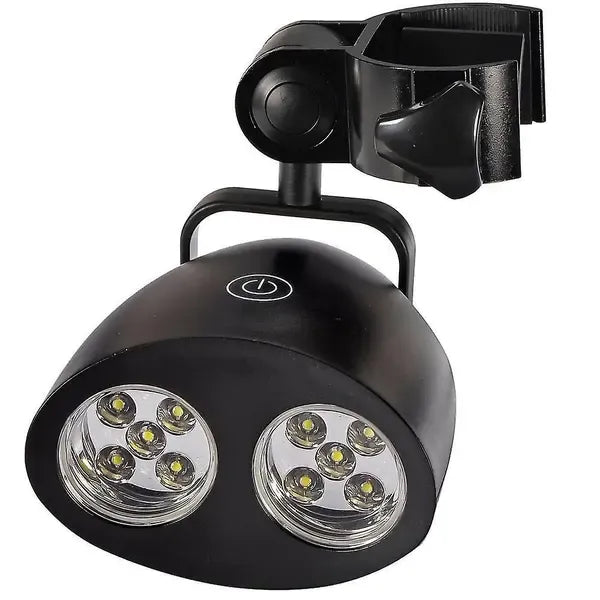 Black clip-on LED grill light clamped to a barbecue handle at night