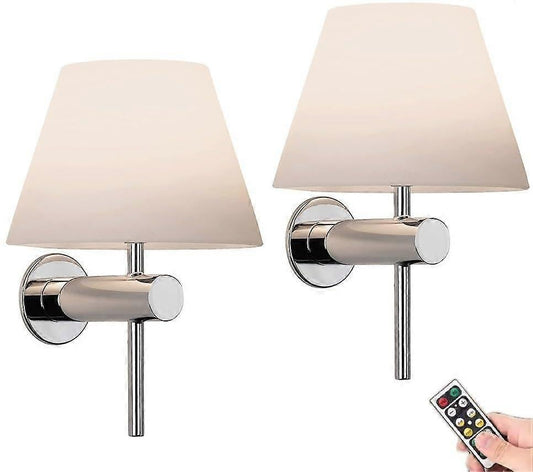 Pair of chrome wall sconces with white linen shades lit on a bedroom wall