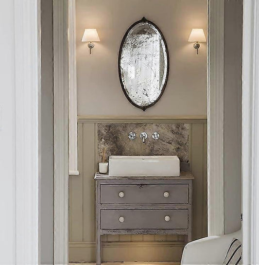 Pair of chrome wall sconces with white linen shades lit on a bedroom wall