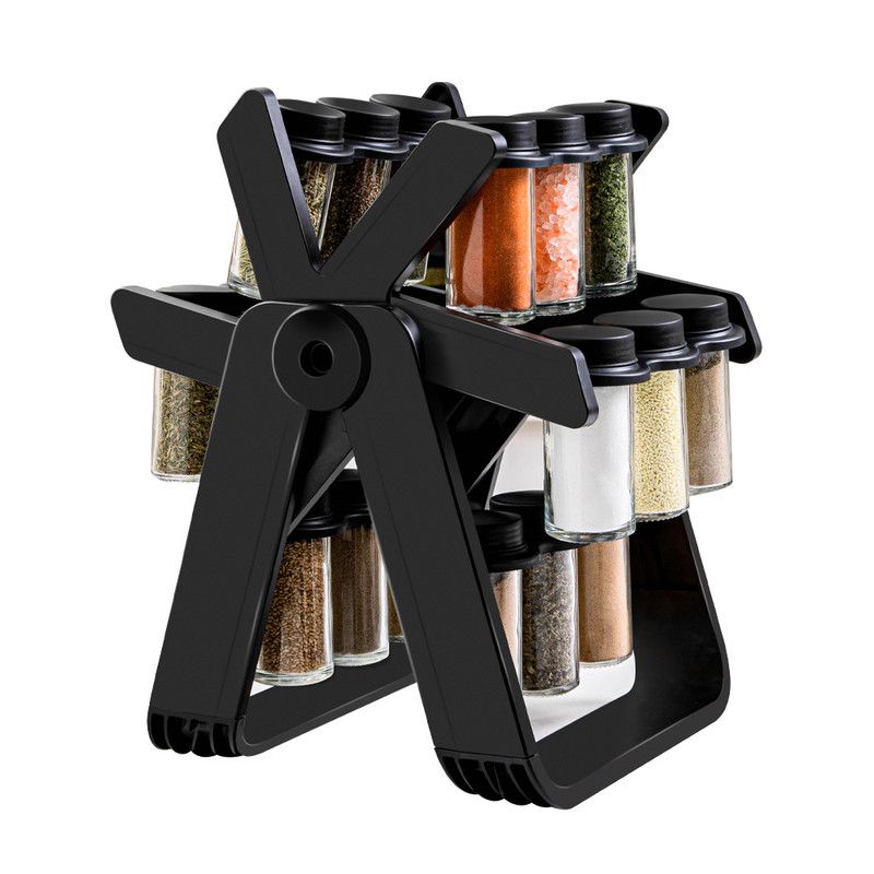 Rotating spice rack holding clear glass spice jars on a kitchen bench