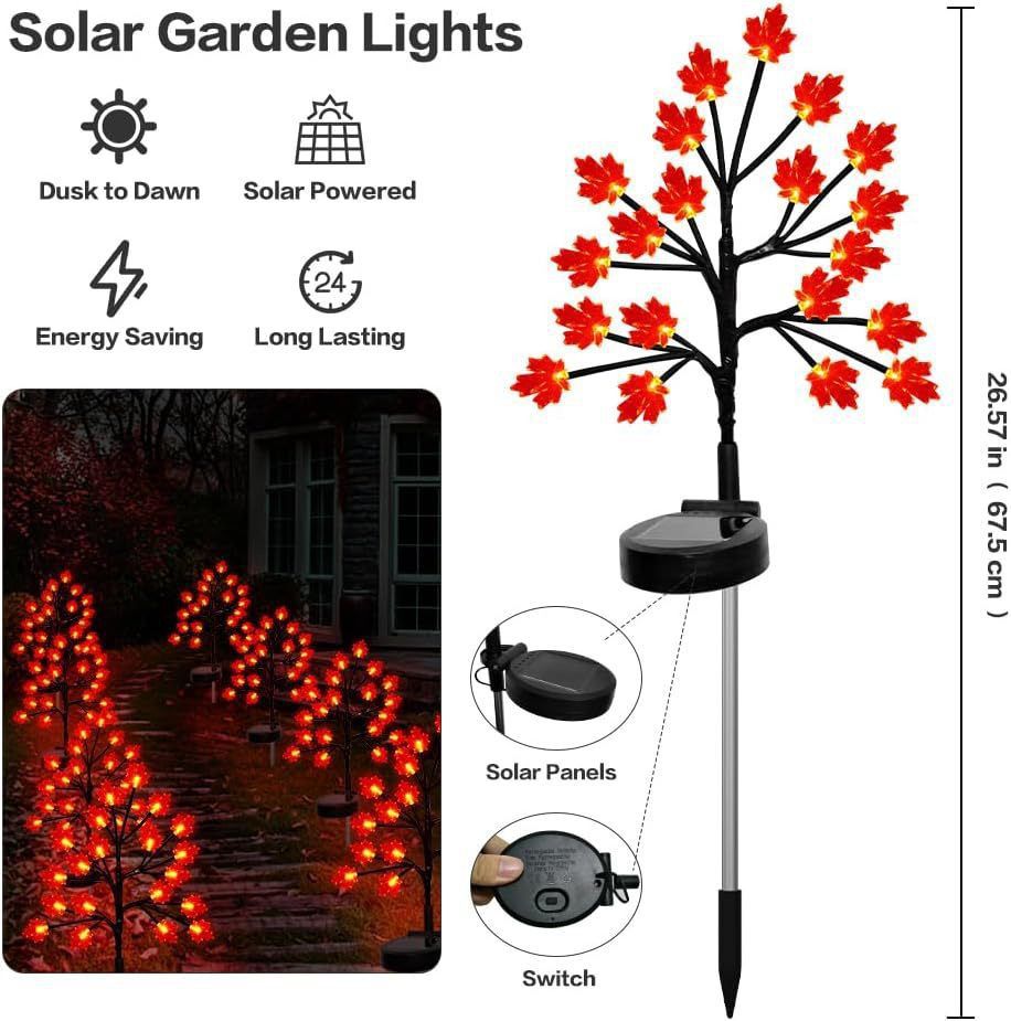 Three solar maple leaf stake lights glowing warm amber in a garden setting