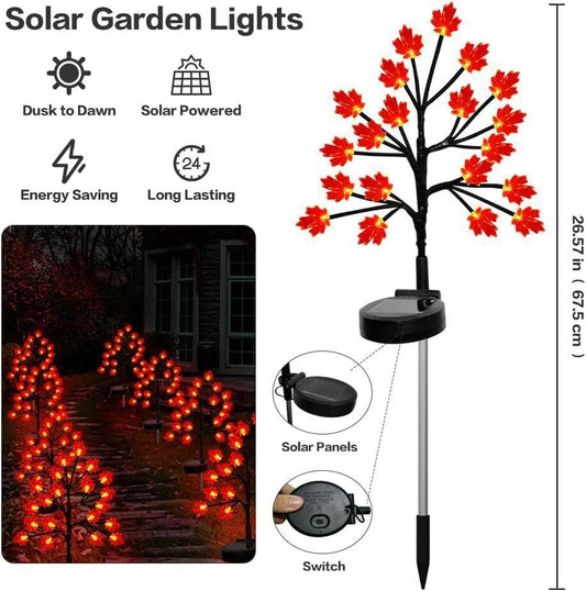 Three solar maple leaf stake lights glowing warm amber in a garden setting