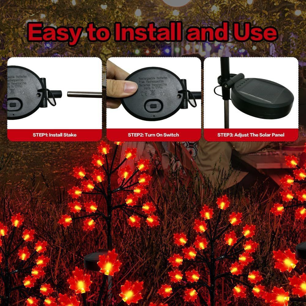 Three solar maple leaf stake lights glowing warm amber in a garden setting