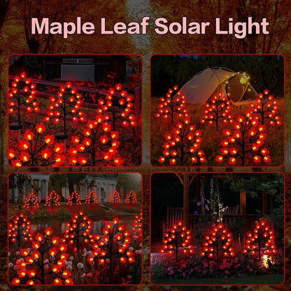 Three solar maple leaf stake lights glowing warm amber in a garden setting