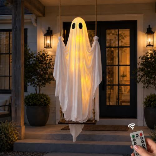 White fabric Halloween ghost hanging from a porch and lit from within