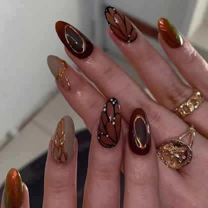 Brown medium almond press-on nails with butterfly wing designs and chrome accents