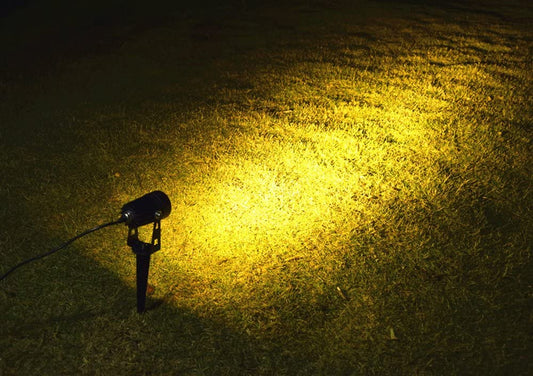 Black aluminium solar garden spotlight uplighting a tree at dusk
