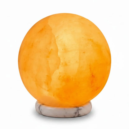 Carved sphere Himalayan pink salt lamp glowing amber on a timber base