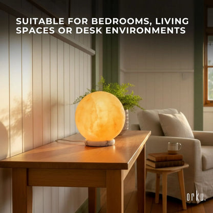 Carved sphere Himalayan pink salt lamp glowing amber on a timber base