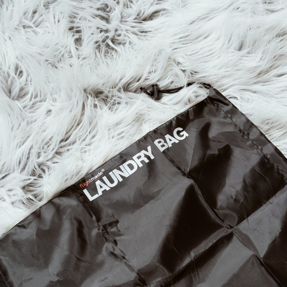 Eight black drawstring laundry bags arranged together