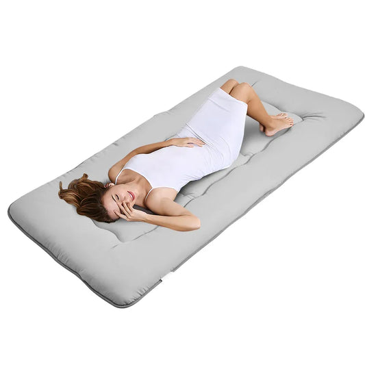 Grey foldable futon mattress with a smooth polyester cover for floor sleeping