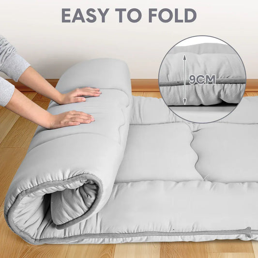 Grey foldable futon mattress with a smooth polyester cover for floor sleeping