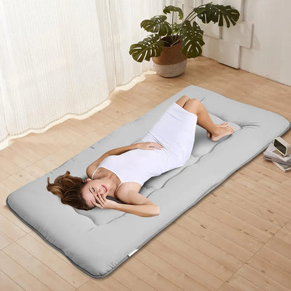 Grey foldable futon mattress with a smooth polyester cover for floor sleeping
