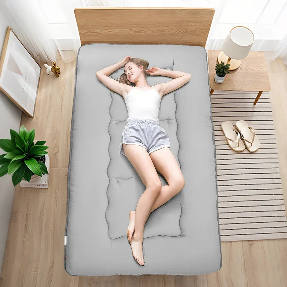 Grey foldable futon mattress with a smooth polyester cover for floor sleeping
